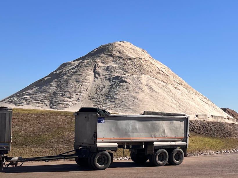 A large stockpile at Glenfield Waste Services with a tipper and dog trailer parked at its foot.